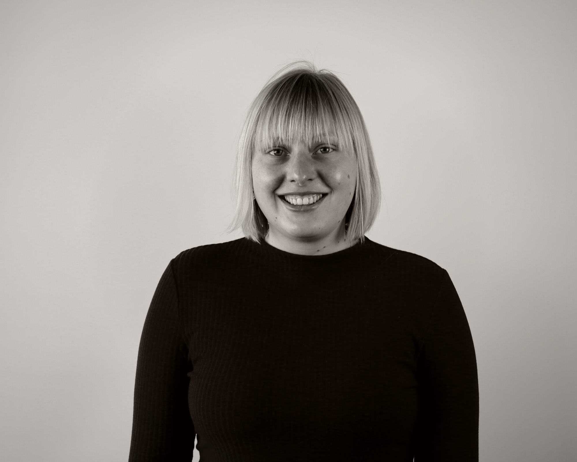 Schwarz-weiß Bild einer in die Kamera lächelnen jungen Frau